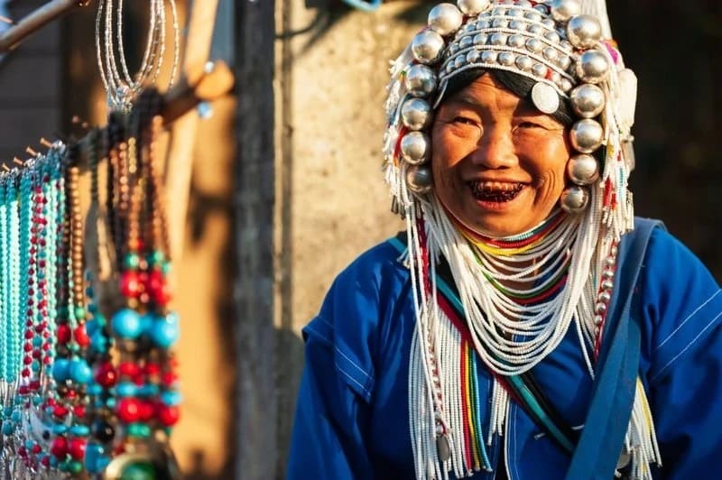 Una donna Akha in abiti tradizionali vende souvenir artigianali