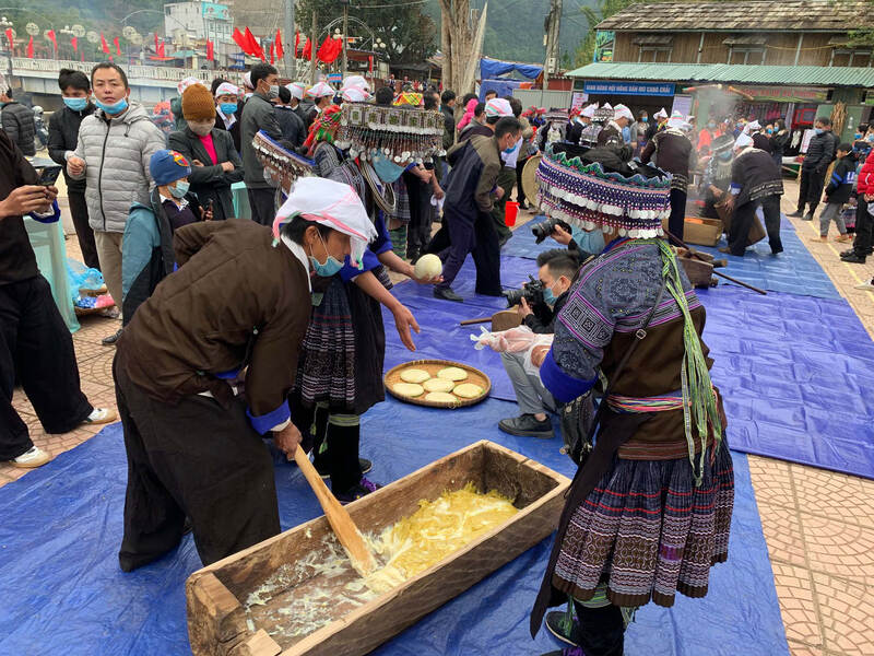 Donne e uomini Hmong pestano e danno forma alle torte di riso