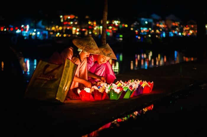 La gente del posto lancia piccole lanterne di carta con candele sul fiume Hoai, Hoi An